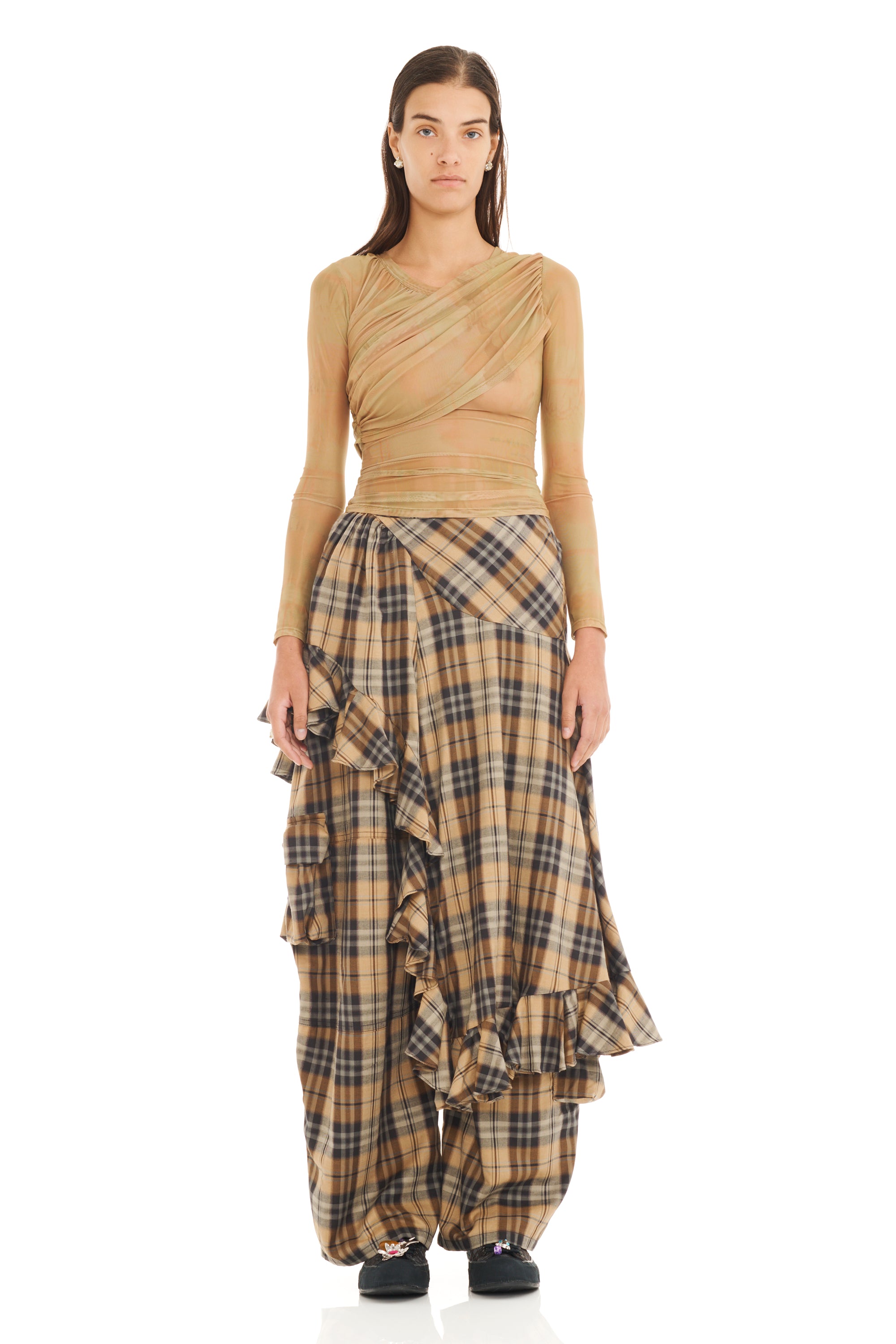 Woman wearing a sheer beige wrap top with long sleeves and plaid skirt on a white background