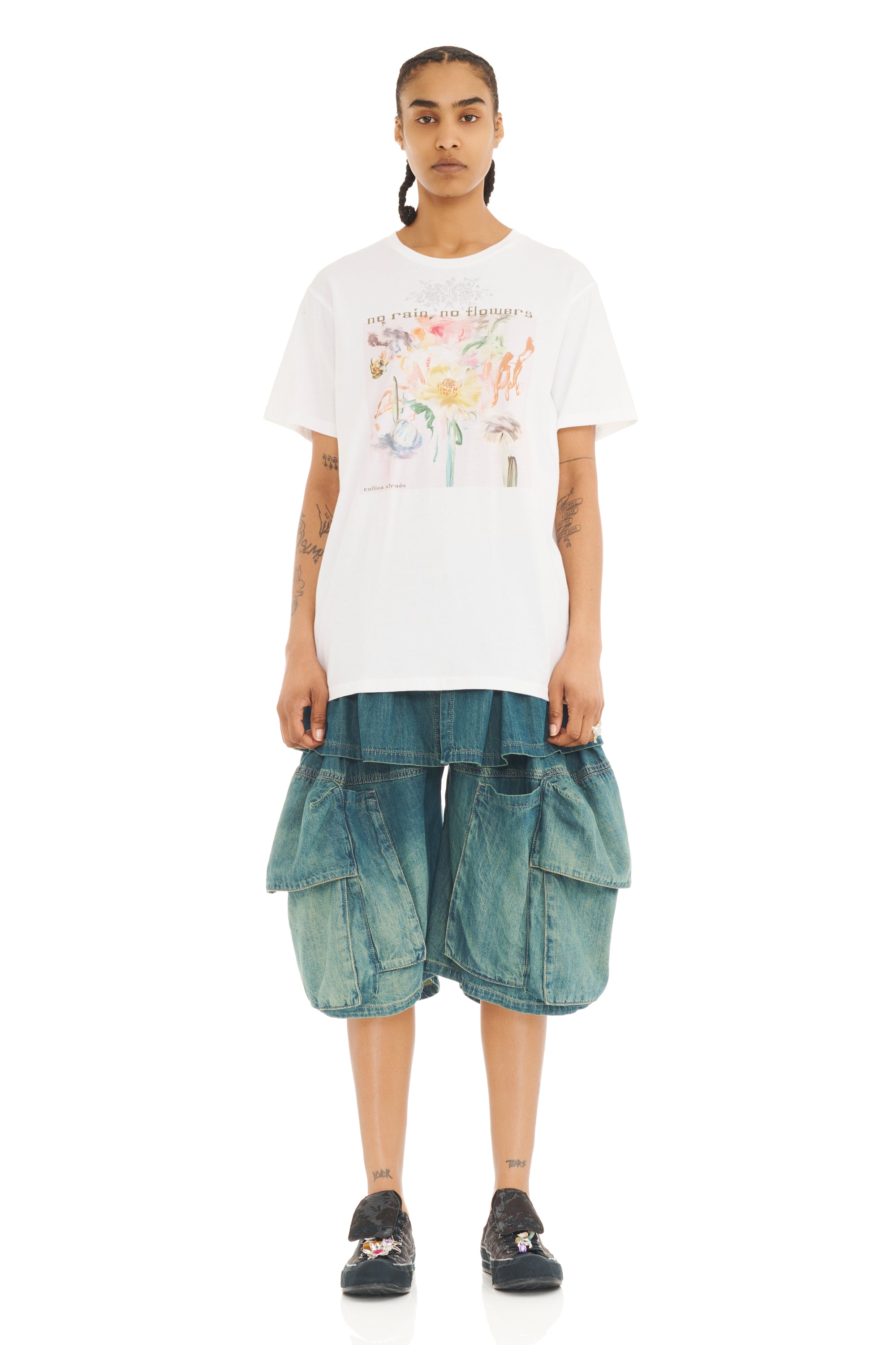 Person wearing a white t-shirt with a pastel floral rhinestone design and blue cargo shorts on a white background