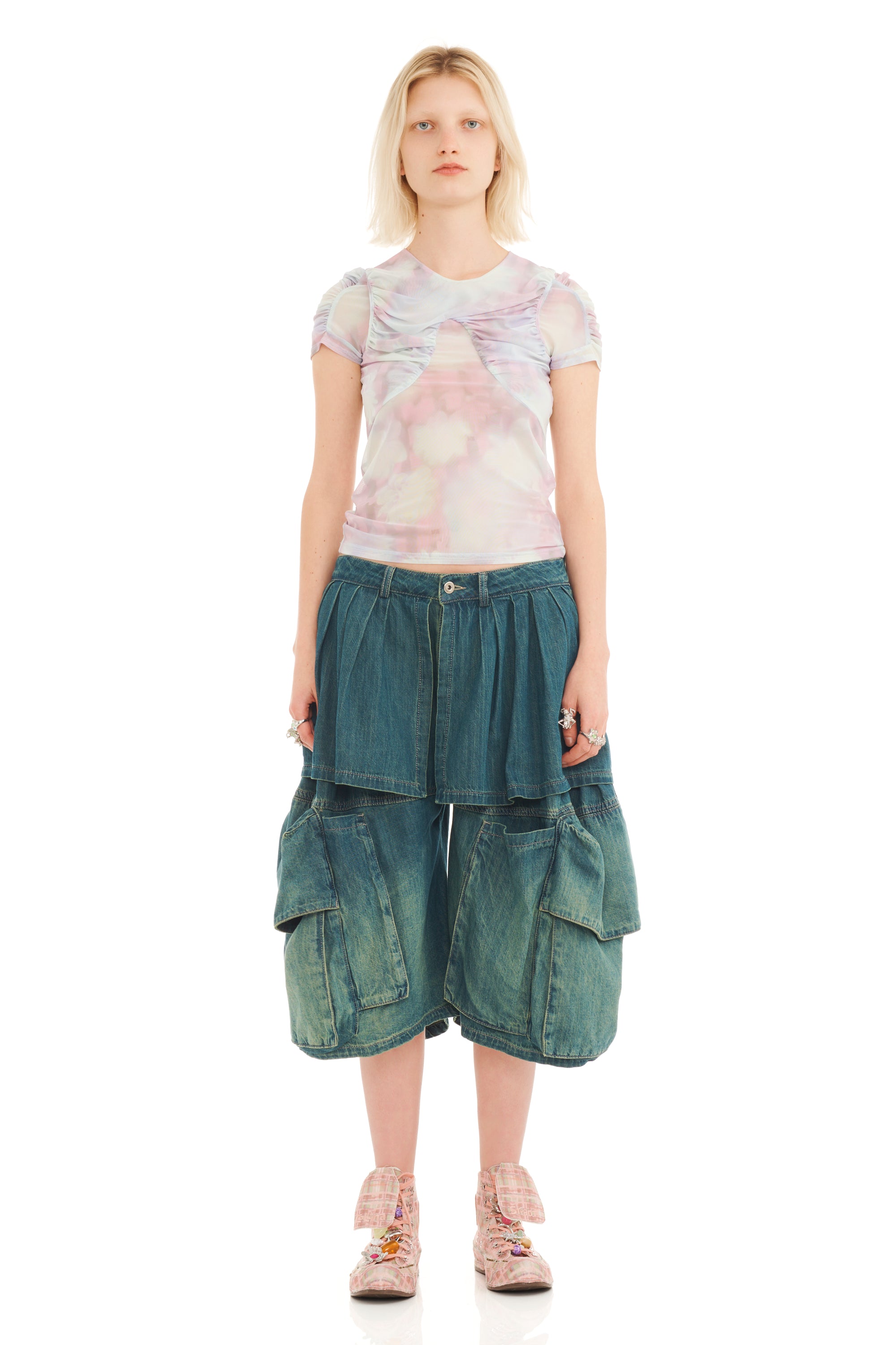 Woman wearing a floral top and oversized denim cargo shorts on a white background