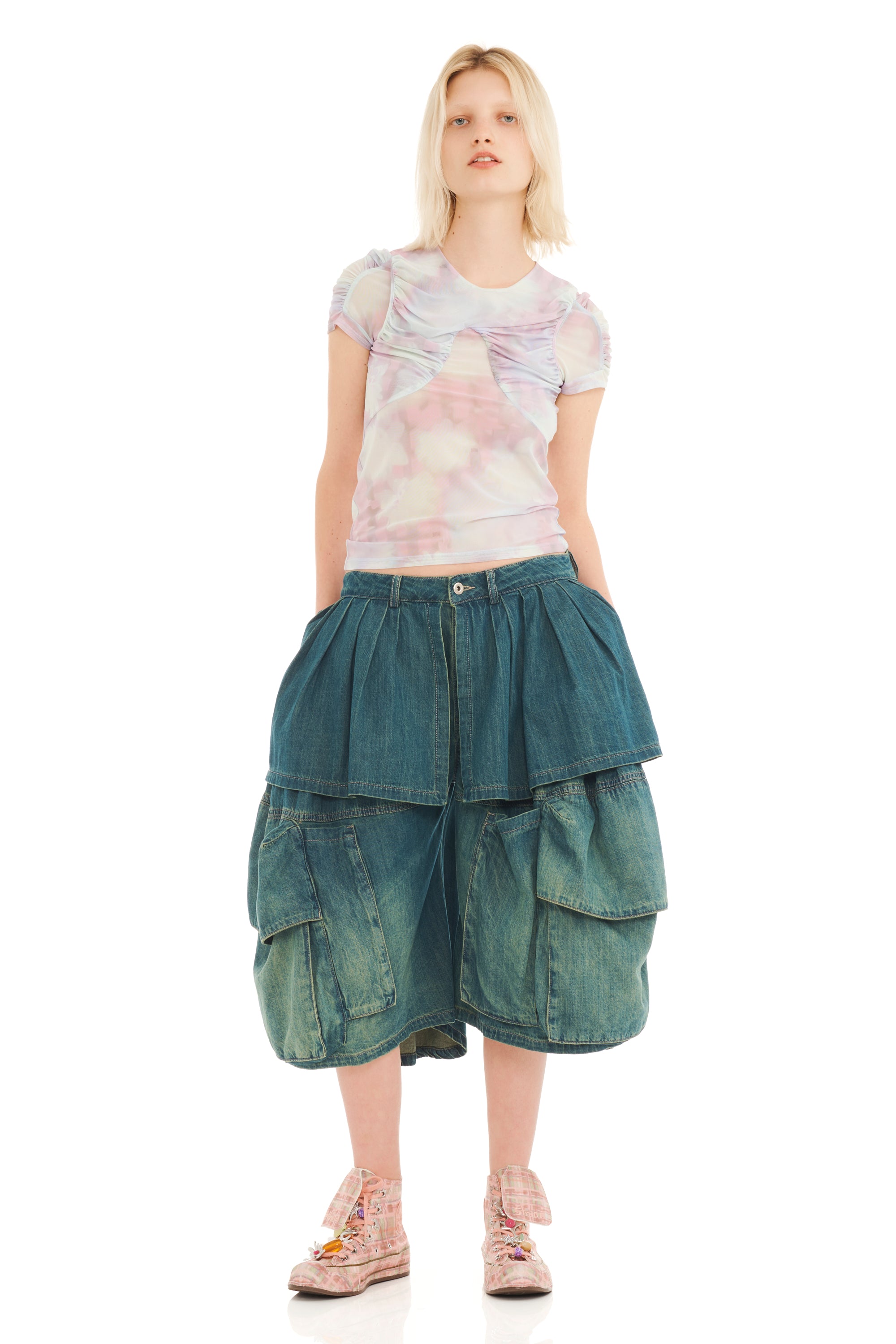 Woman wearing a sheer pastel floral printed mesh t-shirt and oversized denim shorts on a white background