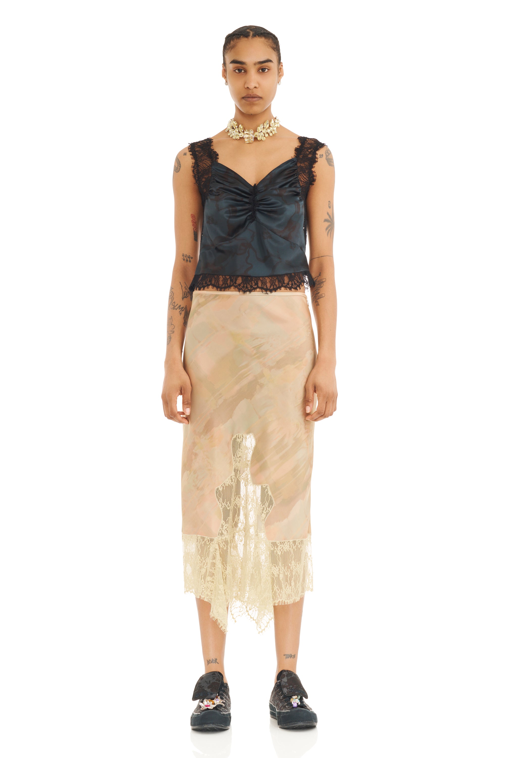 Woman wearing a black lace top and beige sheer skirt on a white background