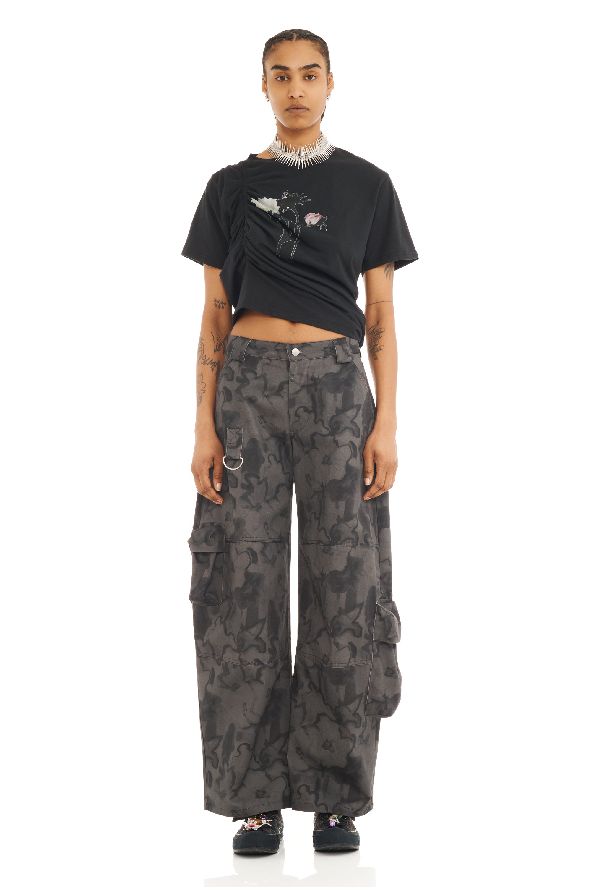 Person wearing a black t-shirt and camouflage cargo pants on a white background