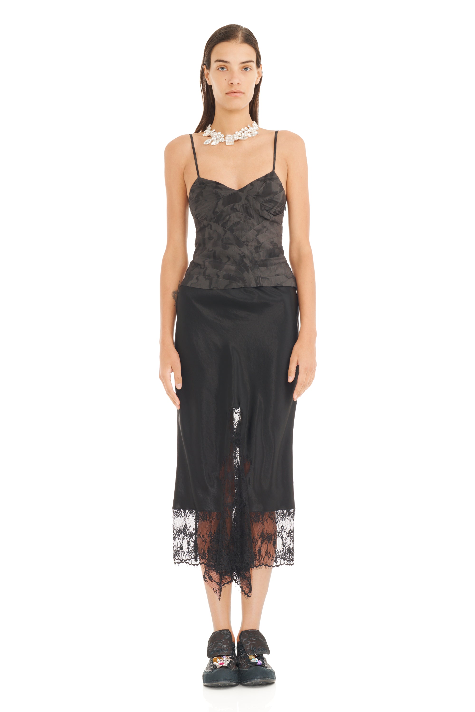 Woman wearing a black watercolor floral pritned fitted camisole with a black lace skirt on a white background