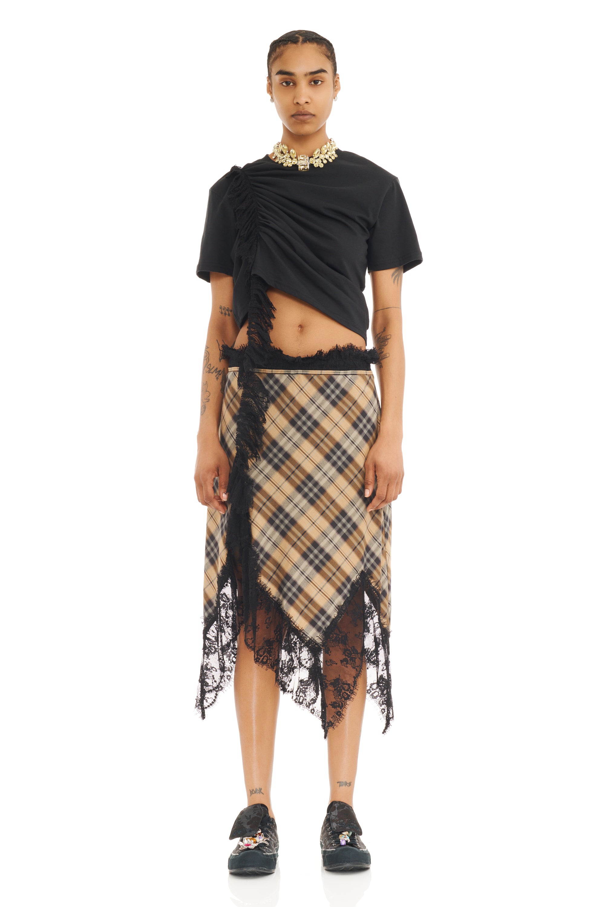 Model wearing a black top and plaid skirt with lace details on a white background
