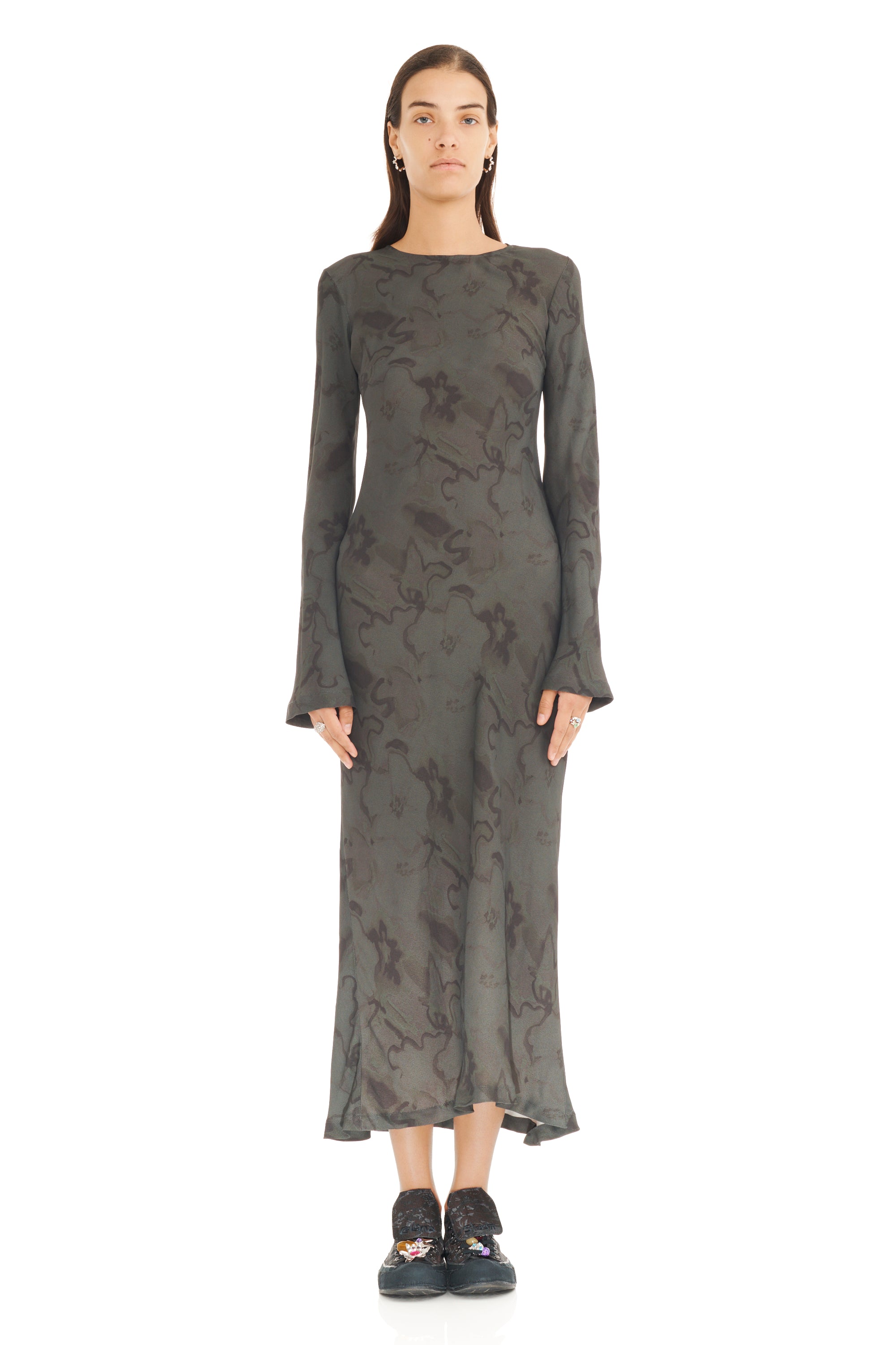 Woman wearing a long, dark gray dress with a subtle pattern on a white background