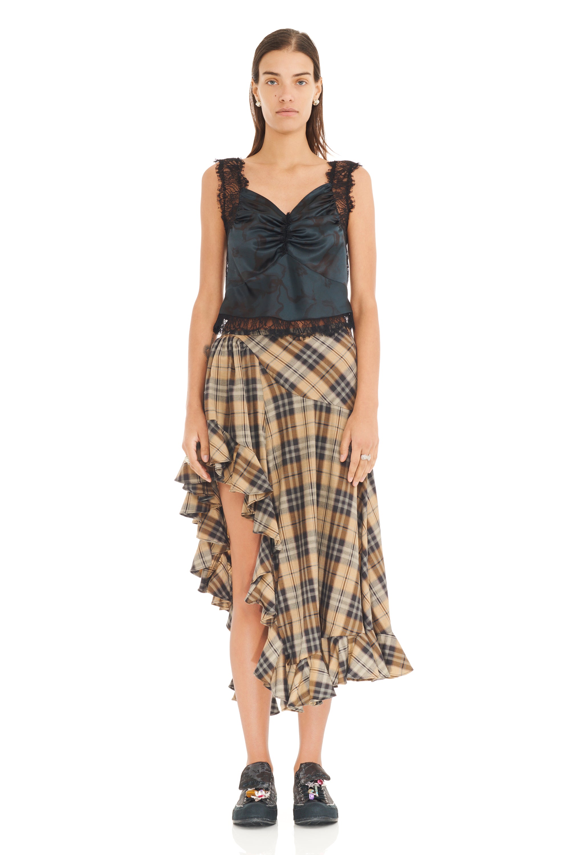 Woman wearing a black top with lace details and a plaid skirt on a white background