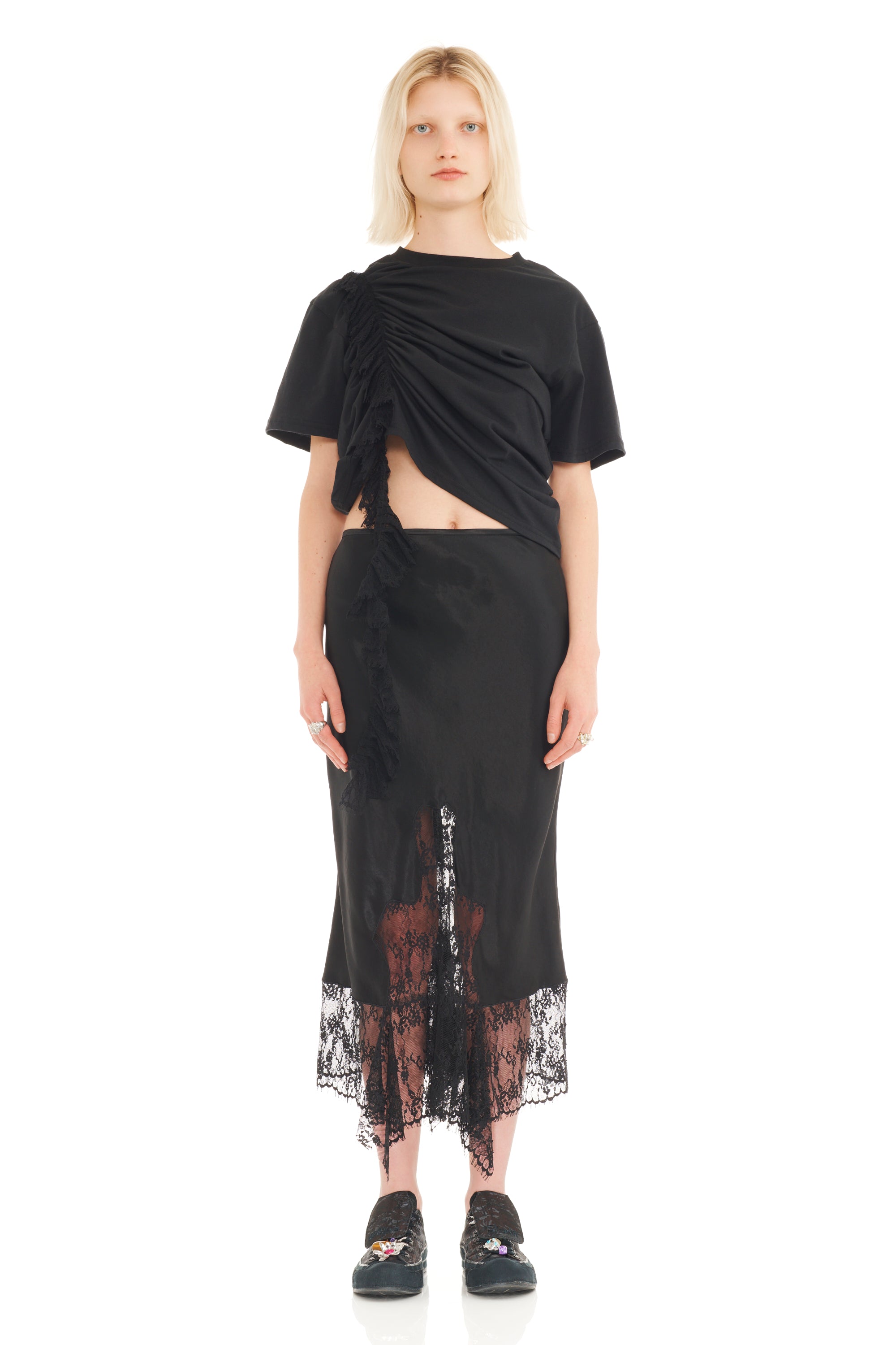Woman wearing a black outfit with a sheer lace hem on a white background
