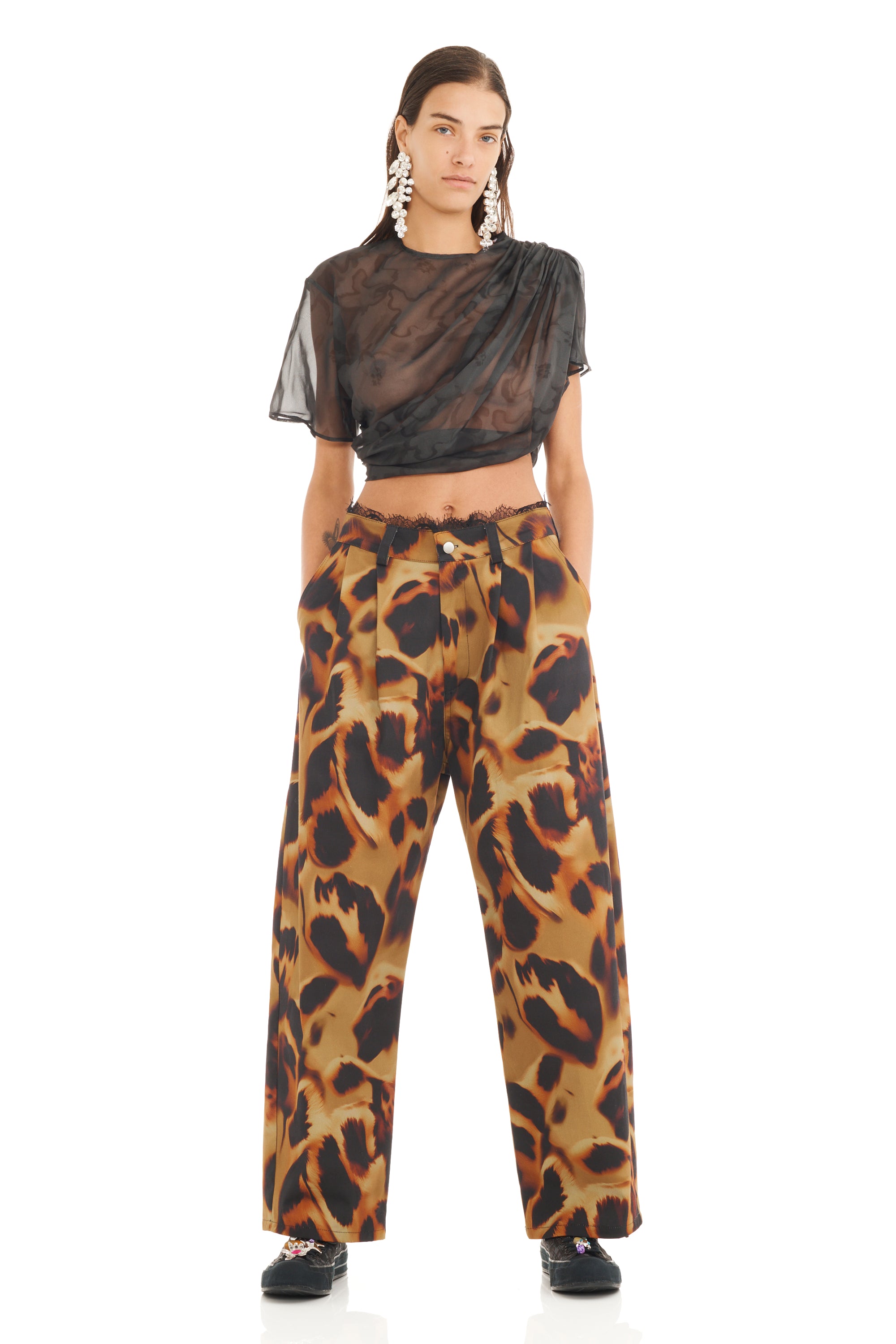 Model wearing sheer black top and leopard print pants with black lace detail on a white background