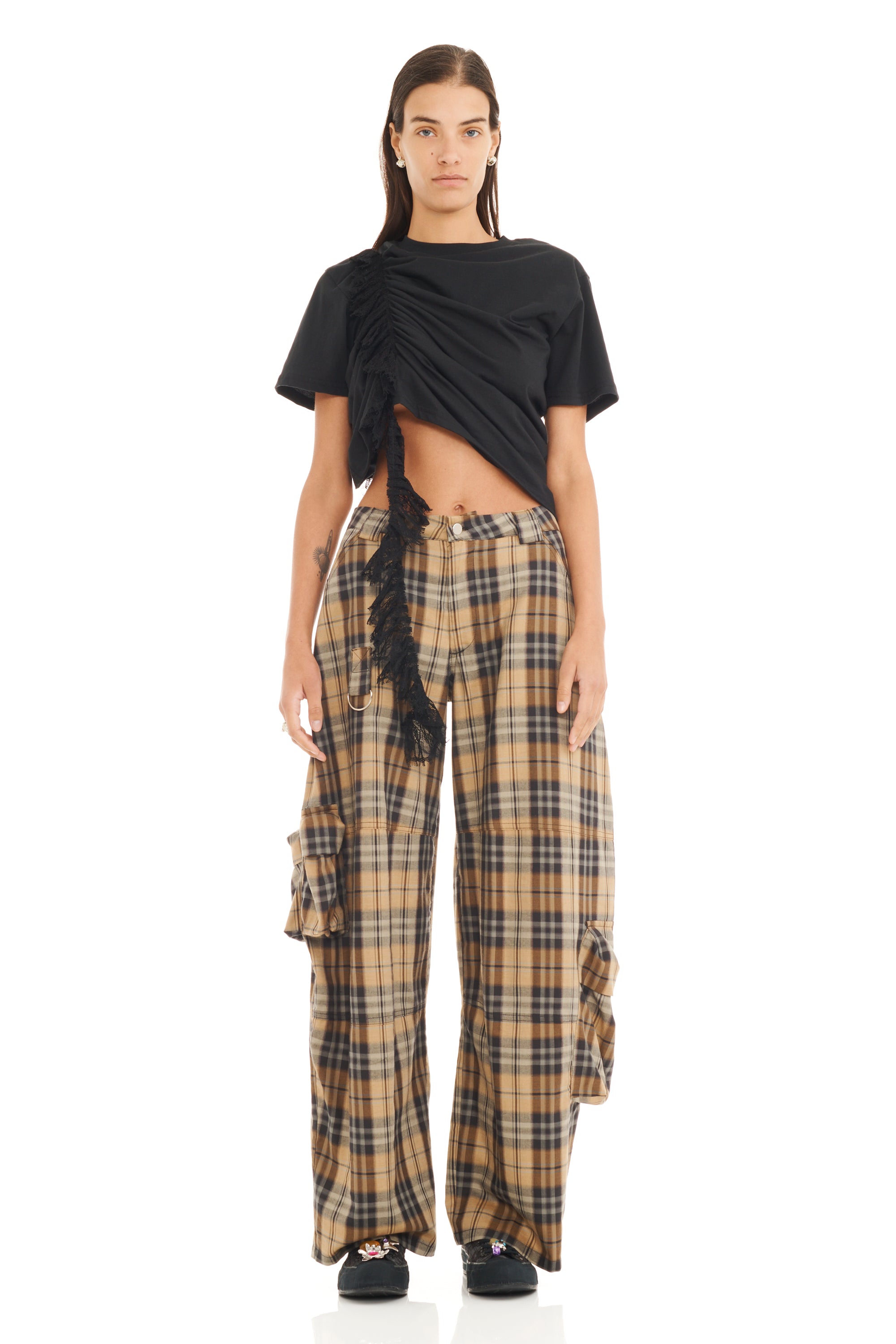Model wearing a black top and plaid pants on a white background