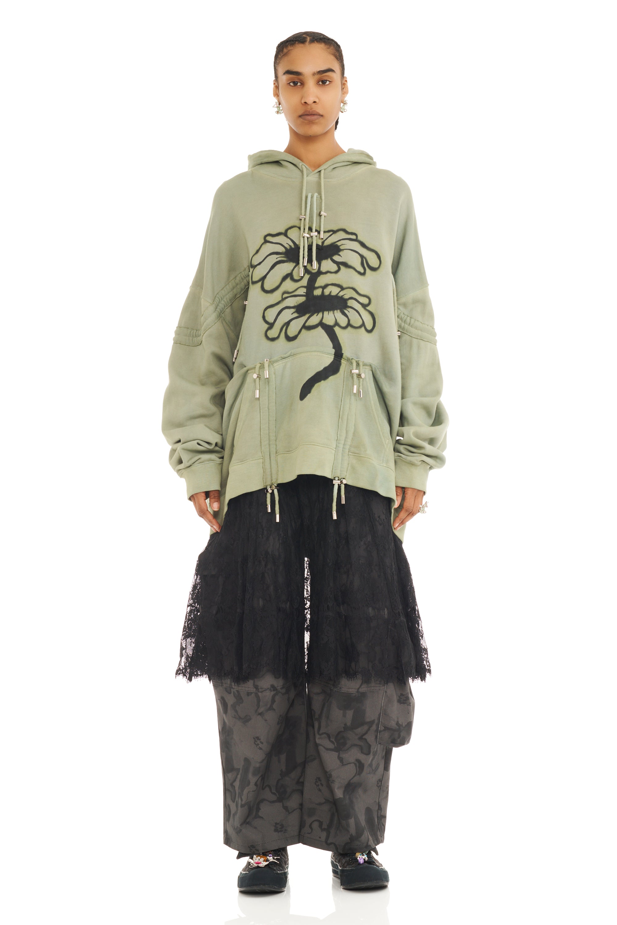 Person wearing a green hoodie with a floral black design on a white background