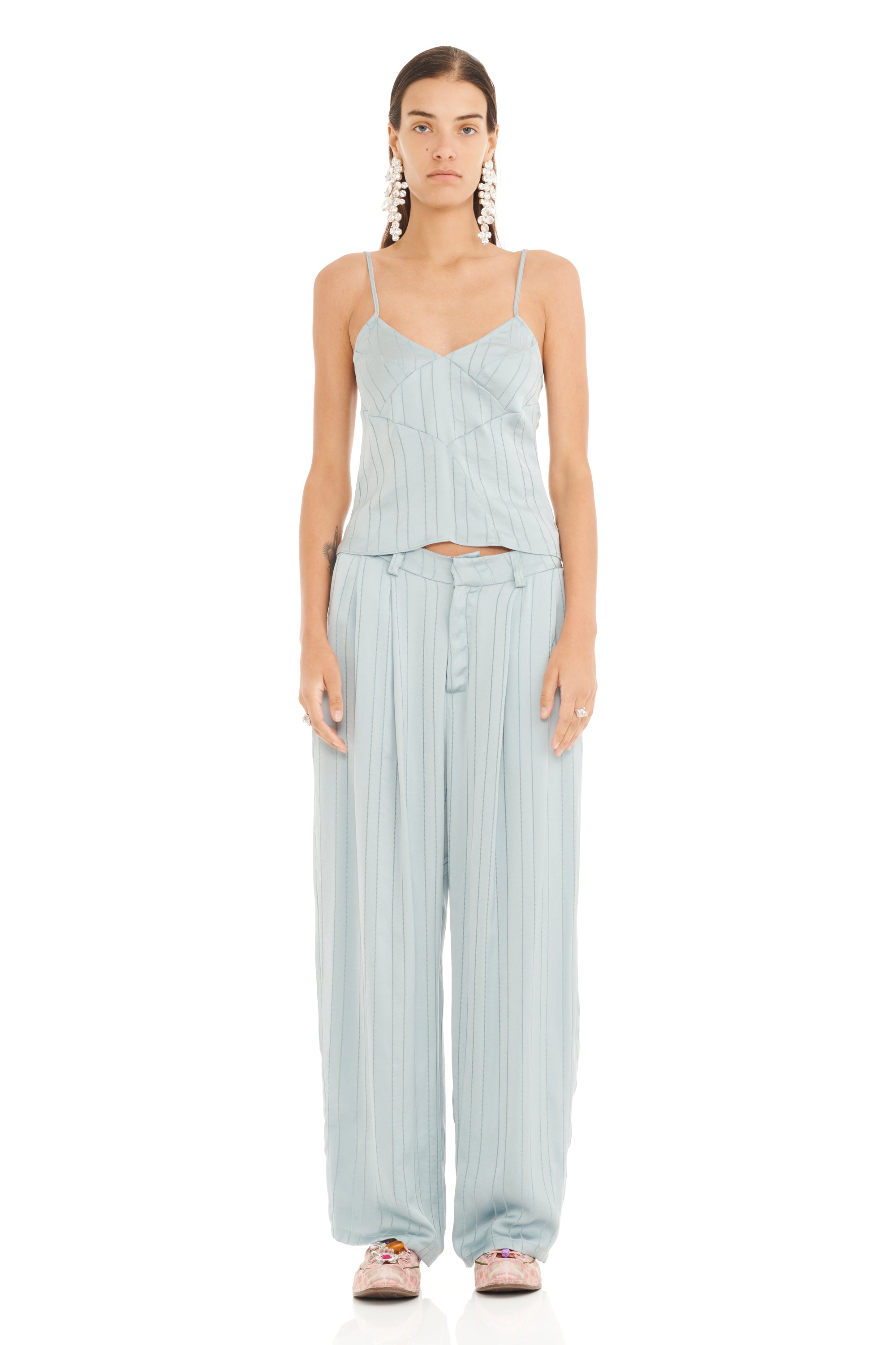 Woman wearing a light blue striped camisole top with matching loose fit trousers on a white background