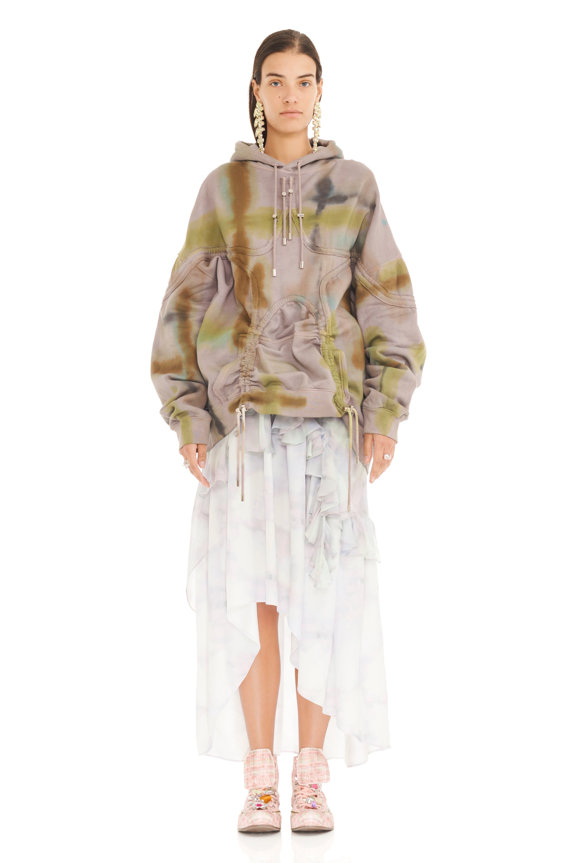 Person wearing a tie-dye hoodie and sheer skirt on a white background